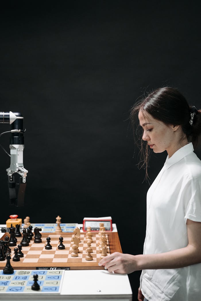 our-story A woman engaged in a strategic chess game with a robotic arm, highlighting AI innovation.