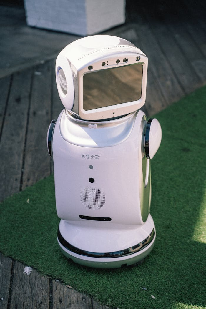 who-we-are A modern robot stands on grass and wooden flooring, showcasing cutting-edge technology.